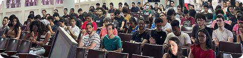 Ampla visão da plateia lotada assistindo a uma palestra no auditório